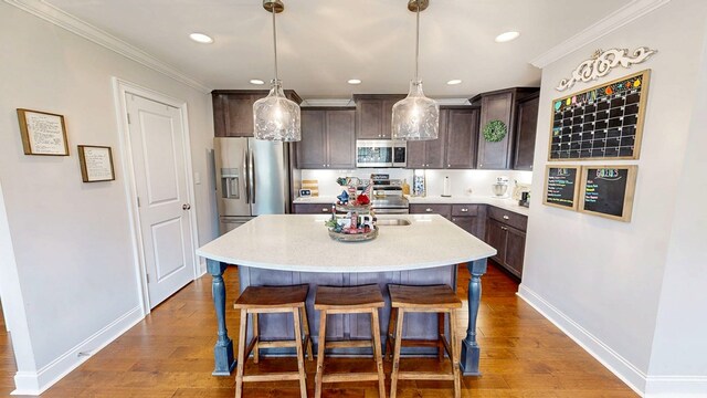 160 Sandbed Rd, Newton, AL 36352 - kitchen with appliances with stainless steel finishes, dark brown cabinets, an island with sink, wood finished floors, and a kitchen bar