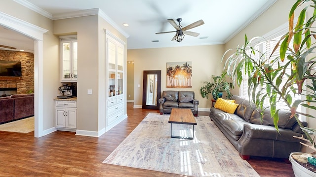 living room featuring ceiling fan, ornamental molding, dark hardwood / wood-style floors, and a fireplace