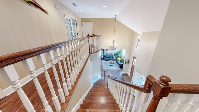 staircase featuring hardwood / wood-style floors, vaulted ceiling, and a chandelier