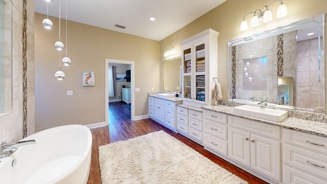 bathroom featuring vanity, a bath, and wood-type flooring