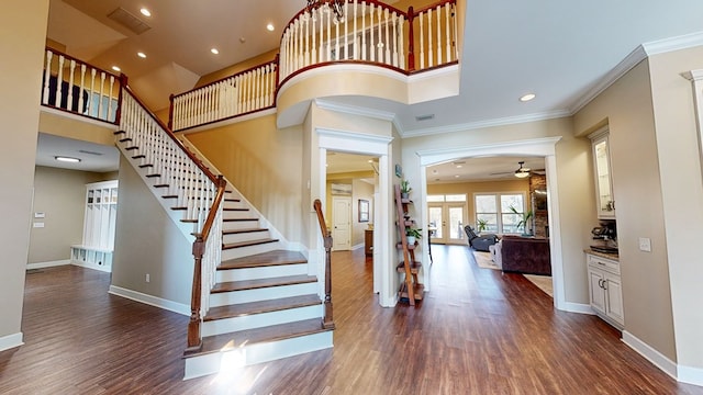 foyer featuring dark hardwood / wood-style flooring, a towering ceiling, ornamental molding, and french doors