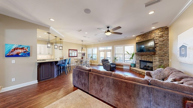 living room with a fireplace, ornamental molding, dark hardwood / wood-style floors, and ceiling fan