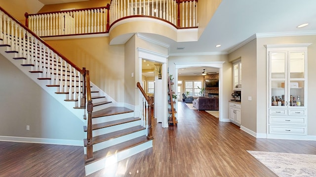 foyer featuring dark hardwood / wood-style flooring, a towering ceiling, ornamental molding, and ceiling fan