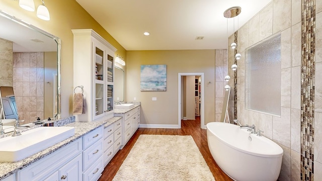 bathroom with wood-type flooring, a bathing tub, vanity, and tile walls