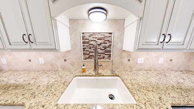 kitchen with white cabinets, light stone counters, and decorative backsplash