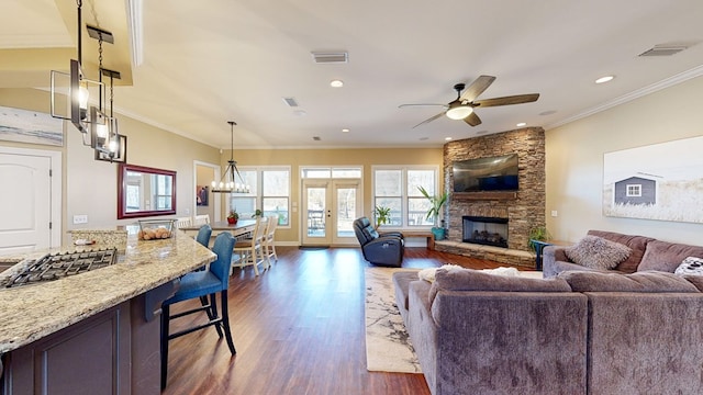 living room featuring ornamental molding, a stone fireplace, dark hardwood / wood-style floors, and french doors