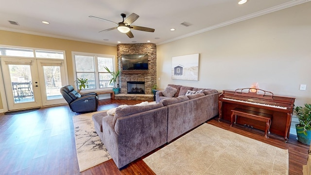 living room featuring a fireplace, hardwood / wood-style flooring, ceiling fan, crown molding, and french doors