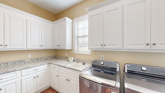 laundry room with cabinets, washing machine and clothes dryer, and sink