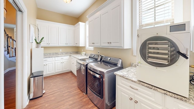 washroom featuring cabinets, hardwood / wood-style floors, and washer and clothes dryer