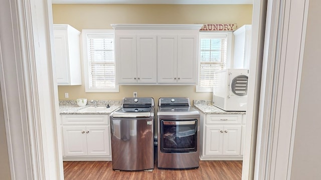 laundry room featuring cabinets, sink, light hardwood / wood-style floors, and washing machine and dryer