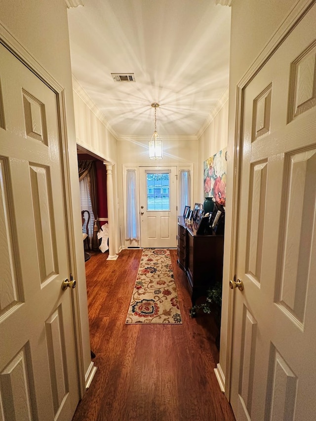 doorway to outside with dark wood finished floors, visible vents, crown molding, and ornate columns