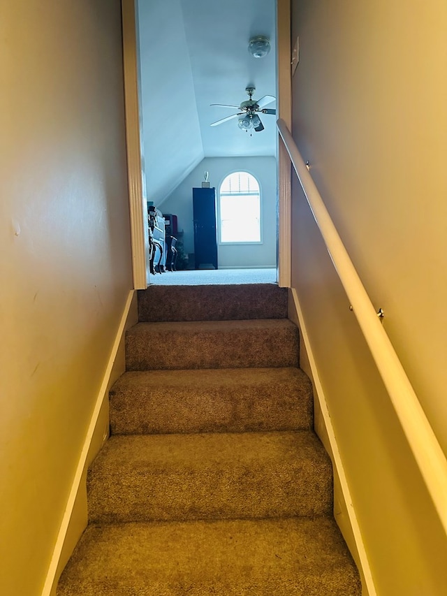 staircase with ceiling fan and vaulted ceiling