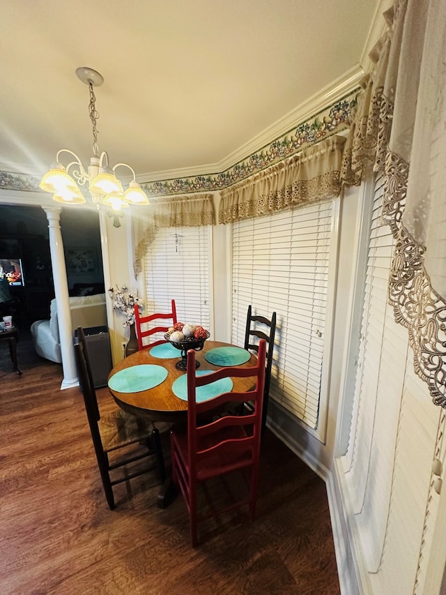 dining area with a chandelier, crown molding, ornate columns, and wood finished floors