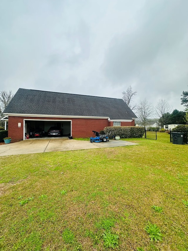 view of side of home with a yard, roof with shingles, concrete driveway, a garage, and brick siding