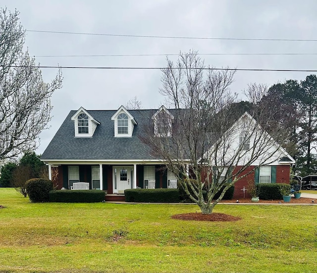 cape cod home with covered porch and a front lawn