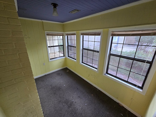 empty room featuring dark carpet, ornamental molding, and wood ceiling