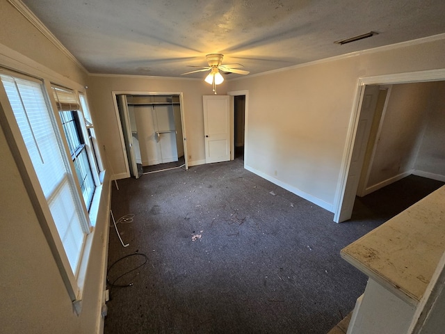 unfurnished bedroom featuring dark carpet, ceiling fan, and crown molding