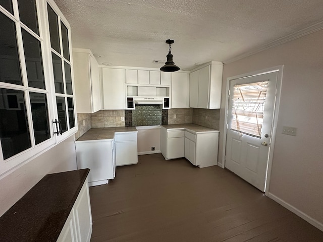 kitchen featuring backsplash, white cabinets, dark wood-type flooring, and baseboards