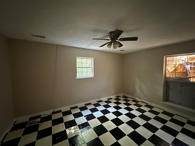 spare room featuring tile patterned floors, visible vents, and a ceiling fan