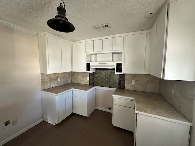 kitchen featuring visible vents, decorative backsplash, dark wood-type flooring, white cabinets, and under cabinet range hood