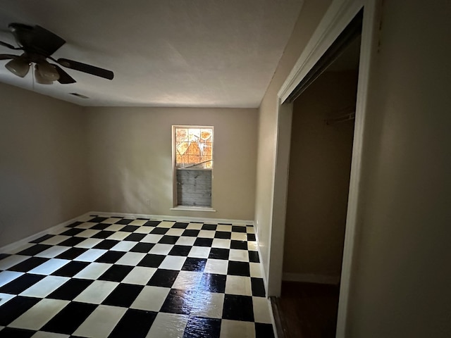 empty room featuring tile patterned floors, visible vents, baseboards, and ceiling fan