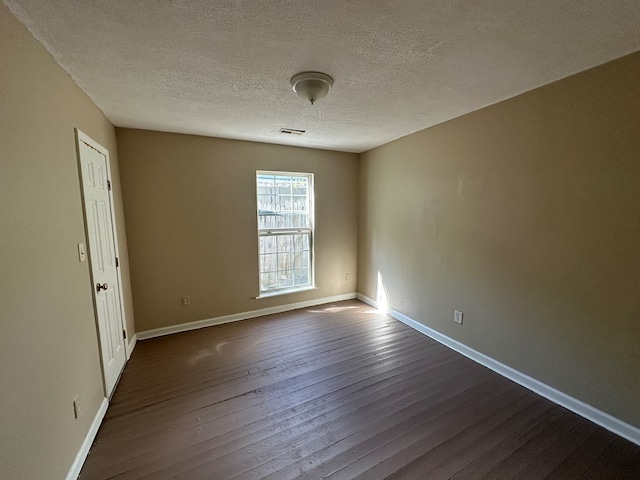 empty room featuring visible vents, baseboards, dark wood-type flooring, and a textured ceiling