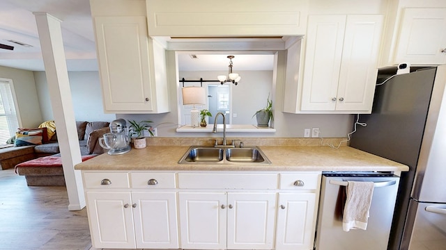 kitchen with a sink, stainless steel appliances, white cabinetry, and a healthy amount of sunlight