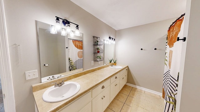 full bathroom with a sink, baseboards, tile patterned flooring, and double vanity