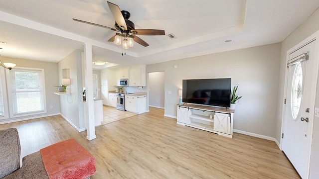 foyer with a ceiling fan, visible vents, light wood-type flooring, baseboards, and a raised ceiling