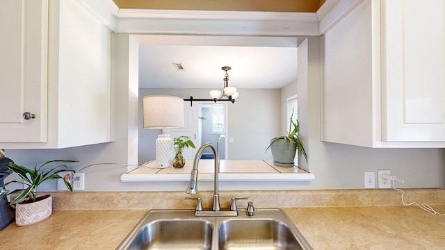 kitchen featuring visible vents, a barn door, light countertops, white cabinets, and a sink