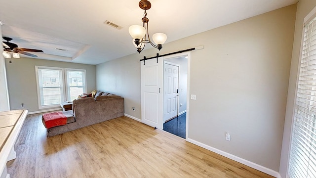 living area featuring ceiling fan, visible vents, a barn door, and light wood-style floors
