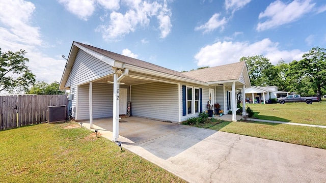 ranch-style house featuring a front lawn, fence, cooling unit, an attached carport, and concrete driveway