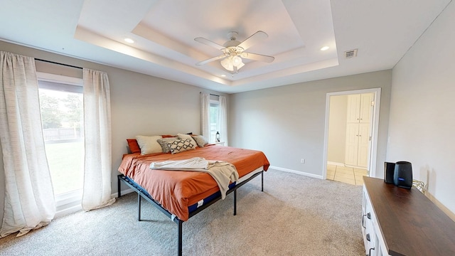 bedroom featuring a raised ceiling, visible vents, light carpet, and multiple windows