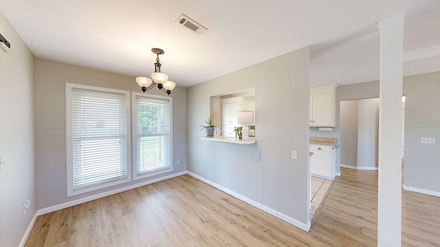 unfurnished dining area featuring visible vents, baseboards, a chandelier, and light wood-type flooring