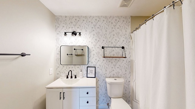 full bathroom featuring vanity, toilet, an accent wall, wallpapered walls, and visible vents