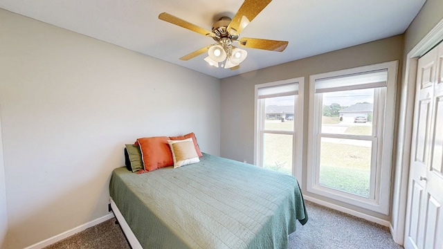carpeted bedroom with a ceiling fan, baseboards, and multiple windows