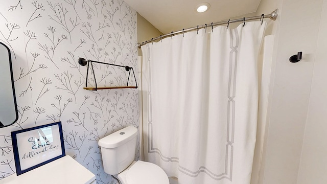bathroom with curtained shower, toilet, and wallpapered walls