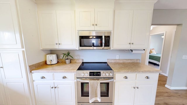 kitchen featuring light wood-type flooring, light countertops, appliances with stainless steel finishes, and white cabinets