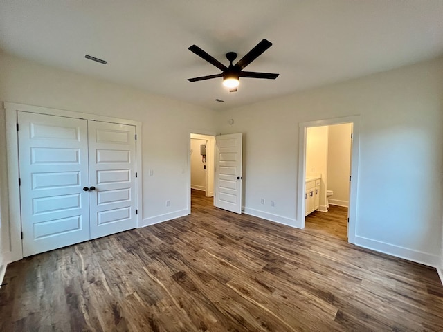 unfurnished bedroom featuring hardwood / wood-style flooring, a closet, ceiling fan, and ensuite bathroom