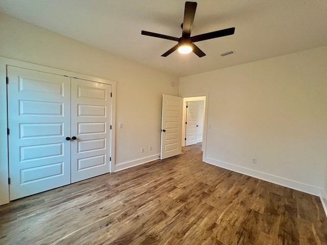 unfurnished bedroom featuring hardwood / wood-style floors, ceiling fan, and a closet