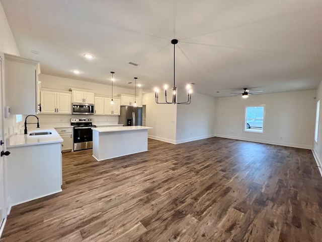 kitchen with pendant lighting, sink, stainless steel appliances, white cabinets, and a kitchen island