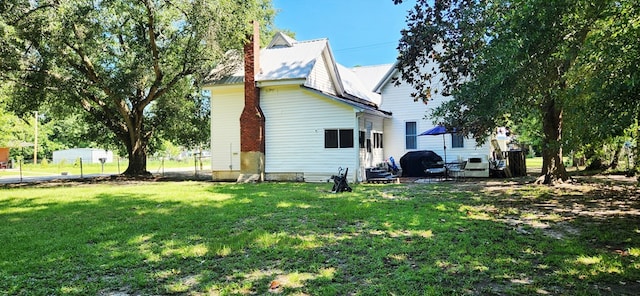 207 W Pullum St, Samson, AL 36477 - view of home's exterior featuring a chimney, a lawn, and a metal roof