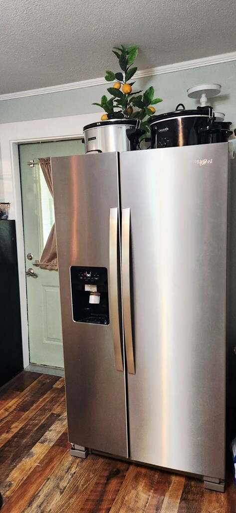 207 W Pullum St, Samson, AL 36477 - detailed view of stainless steel fridge with ice dispenser, dark wood finished floors, a textured ceiling, and ornamental molding