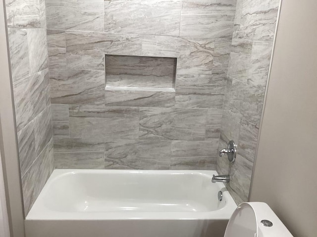 bathroom featuring tiled shower / bath combo and toilet