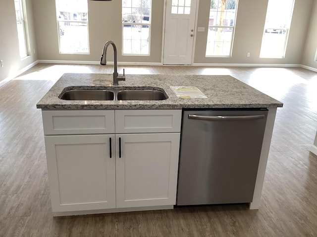 kitchen featuring sink, light stone counters, light wood-type flooring, stainless steel dishwasher, and white cabinets