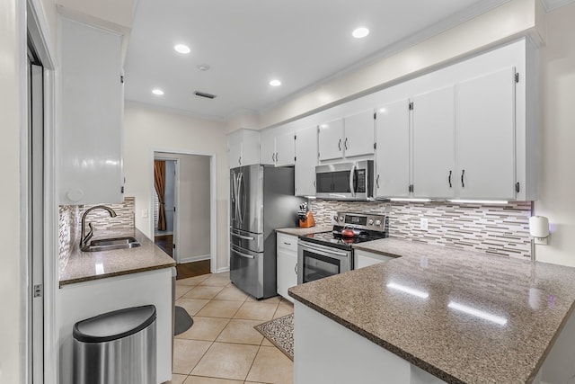 108 Mulberry Ct, Dothan, AL 36303 - kitchen featuring stainless steel appliances, white cabinetry, decorative backsplash, light tile patterned flooring, and dark stone countertops