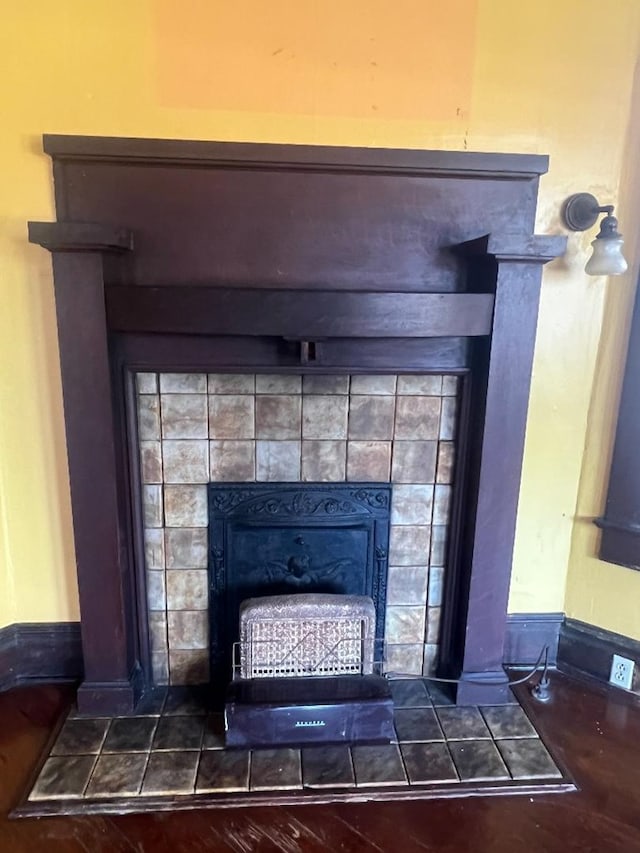 room details with hardwood / wood-style floors and a tiled fireplace