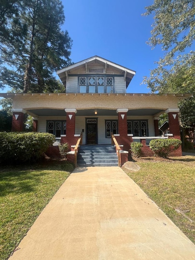 view of front of property featuring covered porch and a front lawn