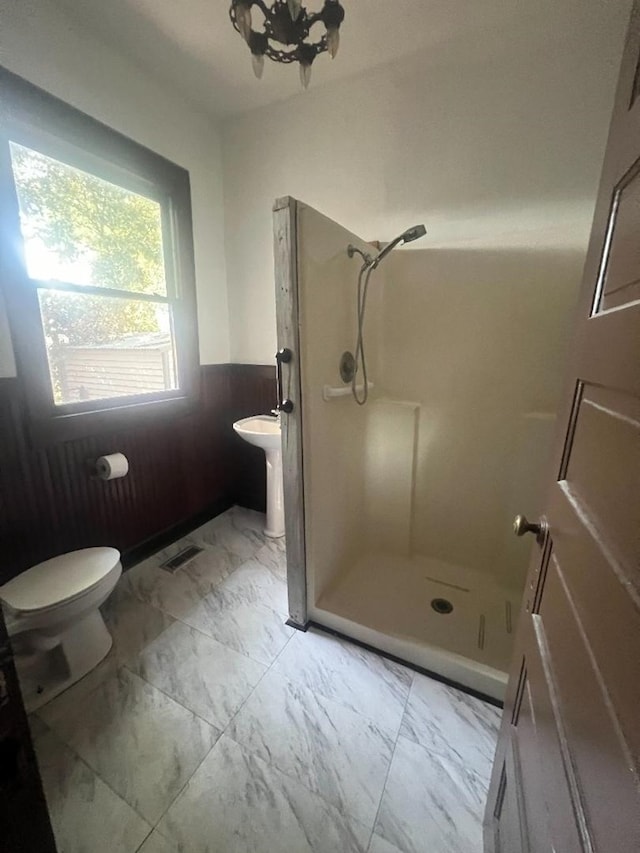 bathroom with a notable chandelier, toilet, and a shower