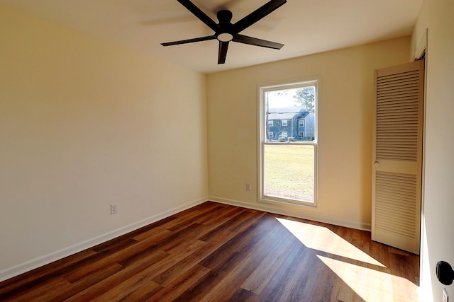 unfurnished room with dark wood-style floors, ceiling fan, and baseboards